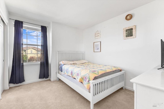 bedroom with light colored carpet and baseboards