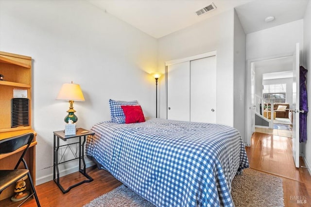 bedroom with visible vents, wood finished floors, a closet, and baseboards