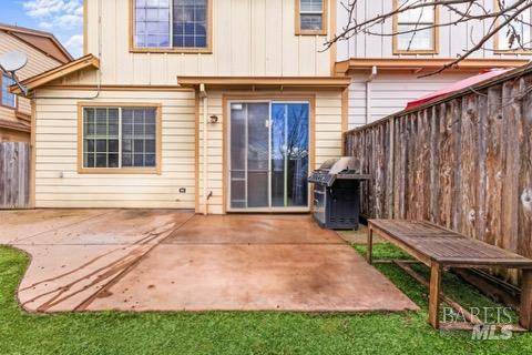 rear view of house featuring a patio area, board and batten siding, and fence