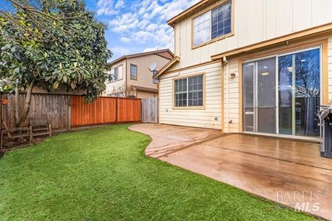 back of house featuring a lawn, a fenced backyard, and a patio area