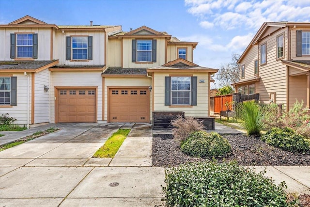 townhome / multi-family property featuring a garage, board and batten siding, driveway, and fence