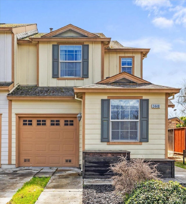 view of front facade featuring board and batten siding, driveway, a garage, and fence