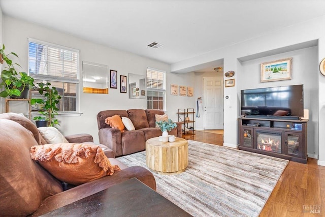 living area with visible vents, baseboards, and wood finished floors