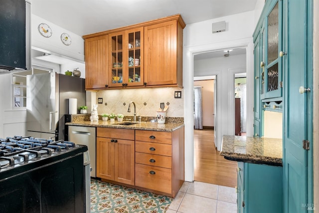 kitchen with backsplash, appliances with stainless steel finishes, dark stone counters, and a sink