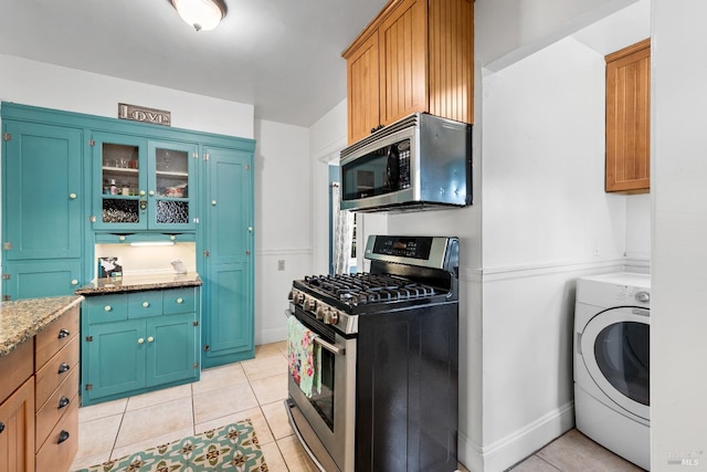 kitchen featuring washer / dryer, light stone counters, light tile patterned flooring, and appliances with stainless steel finishes