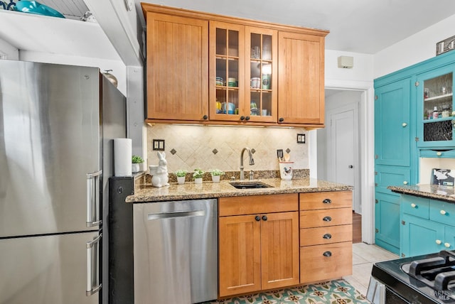 kitchen featuring a sink, appliances with stainless steel finishes, light tile patterned flooring, decorative backsplash, and light stone countertops