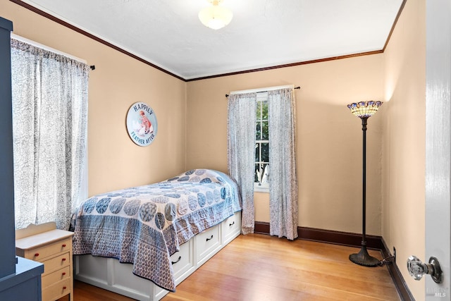 bedroom with crown molding, baseboards, and light wood-type flooring