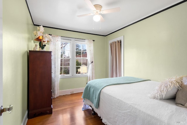 bedroom with ornamental molding, a ceiling fan, baseboards, and wood finished floors