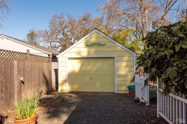 detached garage with gravel driveway and fence