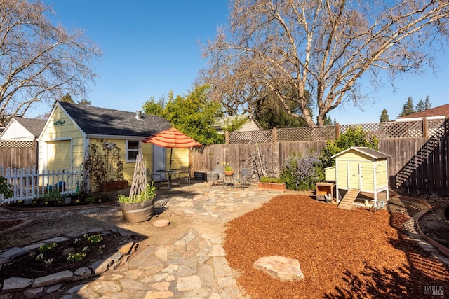 view of yard with an outbuilding, a fenced backyard, a storage unit, and a patio