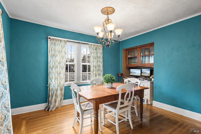 dining area with baseboards, wood finished floors, a notable chandelier, and ornamental molding