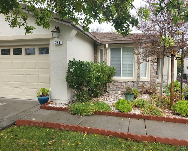 view of front of house with a garage, stucco siding, and stone siding