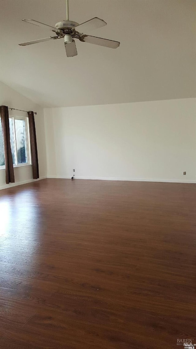 unfurnished room with dark wood-style floors, lofted ceiling, baseboards, and ceiling fan