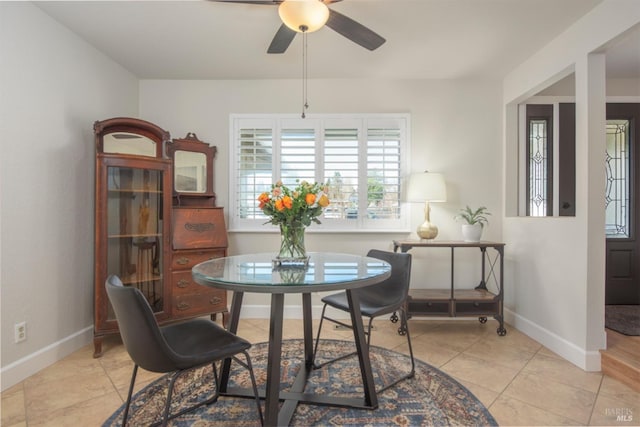 tiled dining area featuring a ceiling fan and baseboards