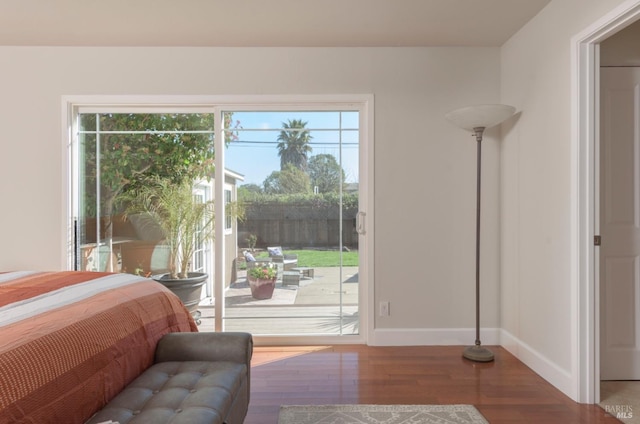 bedroom with wood finished floors, baseboards, and access to outside