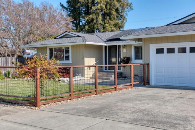 ranch-style home featuring solar panels, an attached garage, a shingled roof, a fenced front yard, and driveway