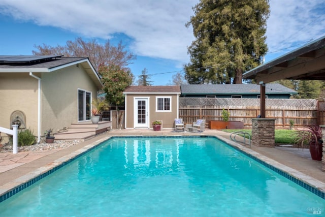 view of swimming pool featuring a fenced in pool, a storage structure, fence, a patio area, and an outbuilding