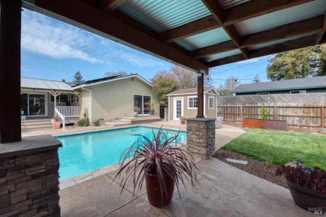 view of swimming pool with a fenced in pool, fence, an outbuilding, and a patio area