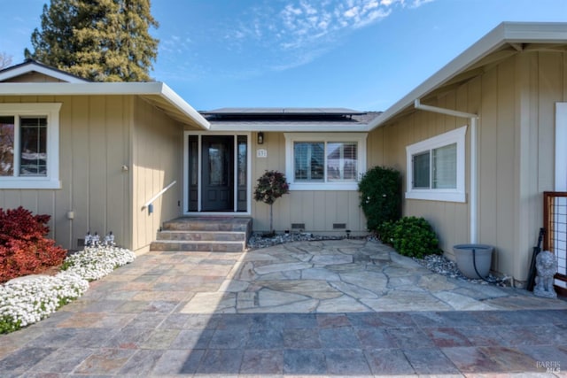 doorway to property with a patio, board and batten siding, and solar panels