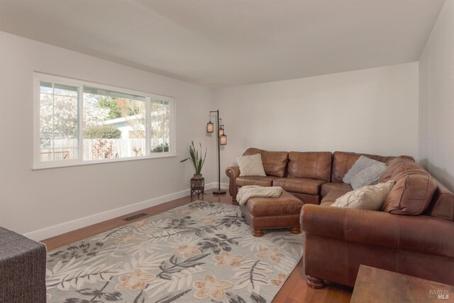 living area with visible vents, baseboards, and wood finished floors