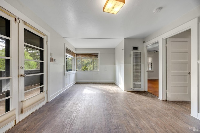 spare room with wood finished floors, a heating unit, and wainscoting