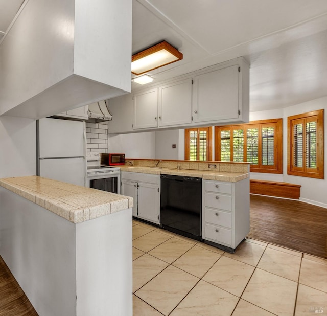 kitchen with white appliances, ventilation hood, light tile patterned floors, a peninsula, and white cabinetry