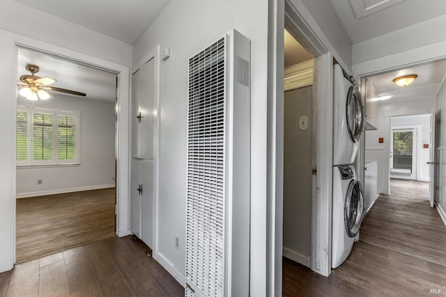 hall featuring dark wood-style floors, attic access, a heating unit, stacked washer and dryer, and a wealth of natural light