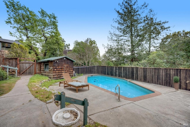 view of swimming pool featuring a patio, a fenced backyard, a fenced in pool, and an outdoor structure