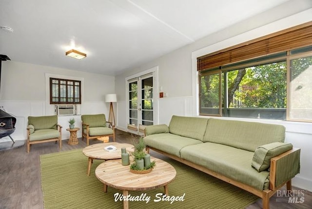 living room with french doors, wood finished floors, wainscoting, and a decorative wall