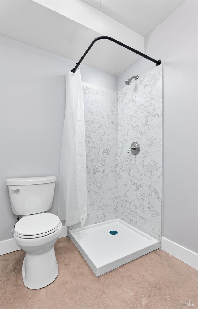 full bathroom featuring a shower stall, toilet, and baseboards