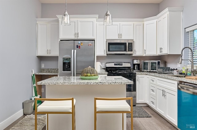 kitchen featuring a toaster, light stone counters, stainless steel appliances, white cabinetry, and a sink