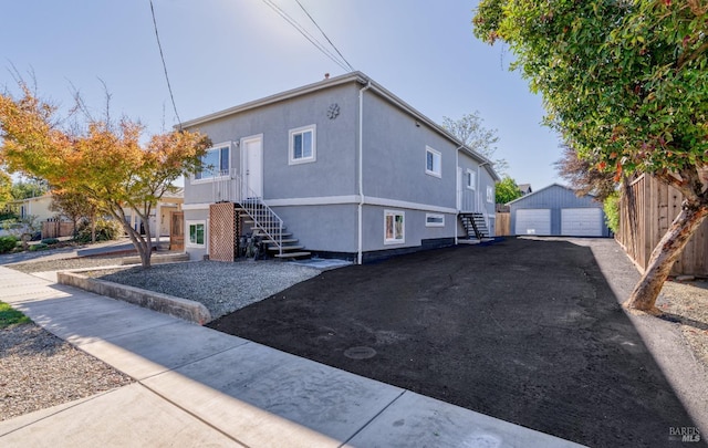 view of home's exterior with an outbuilding, fence, stucco siding, entry steps, and a garage