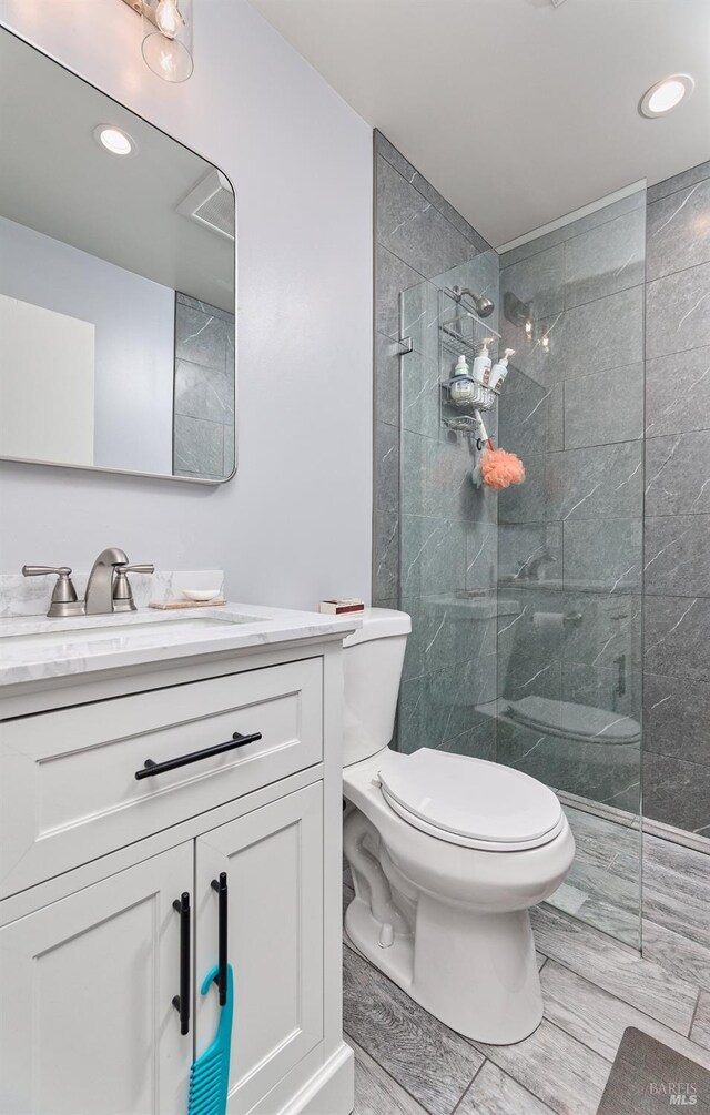 bathroom with vanity, toilet, recessed lighting, and walk in shower