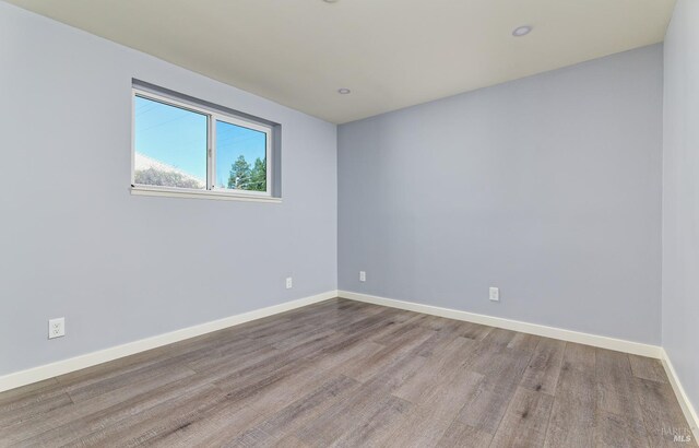 spare room with recessed lighting, wood finished floors, and baseboards
