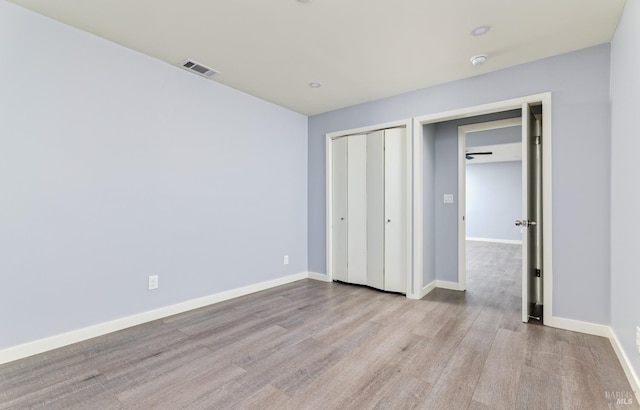 unfurnished bedroom featuring light wood-style flooring, baseboards, visible vents, and a closet
