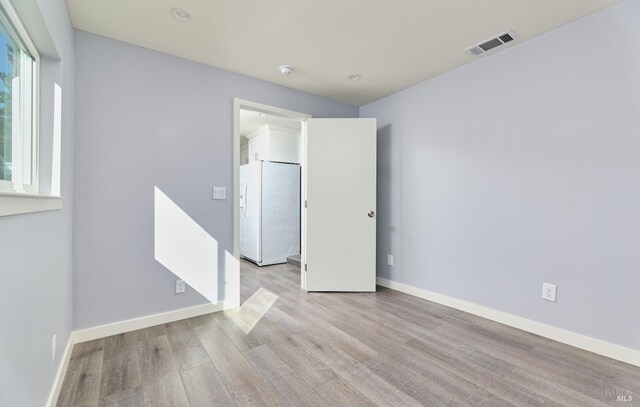 empty room with baseboards, visible vents, and light wood-type flooring