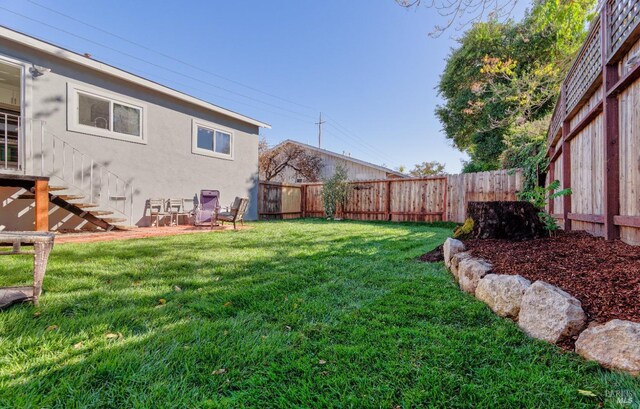 back of house featuring an outdoor structure, a yard, a fenced backyard, and stucco siding