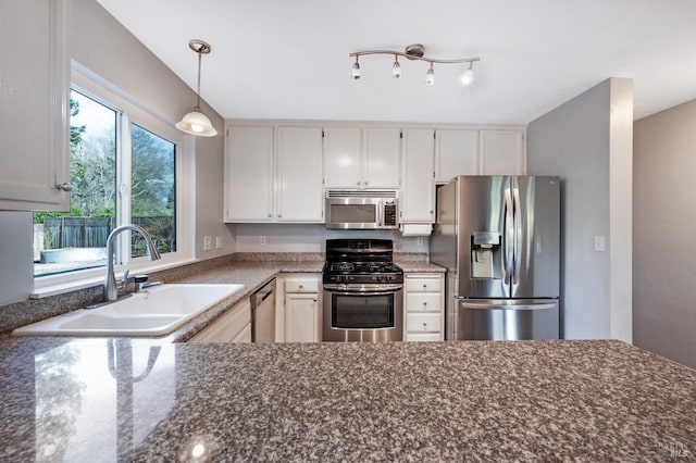 kitchen with a sink, decorative light fixtures, white cabinetry, and stainless steel appliances