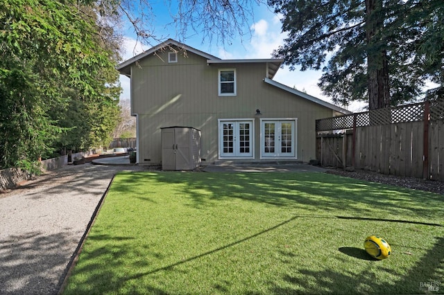 back of house featuring french doors, a lawn, and a fenced backyard