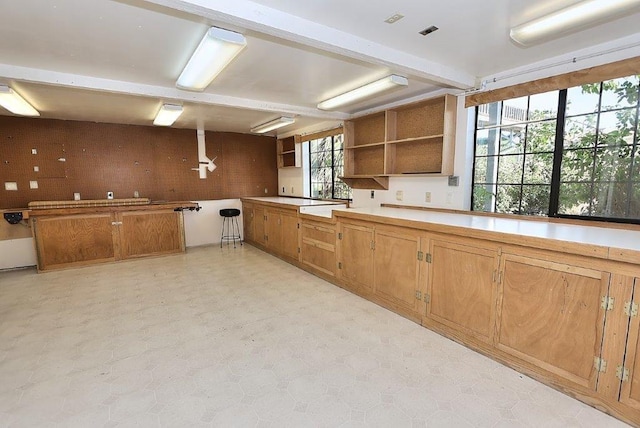 kitchen with open shelves, brown cabinetry, and light floors