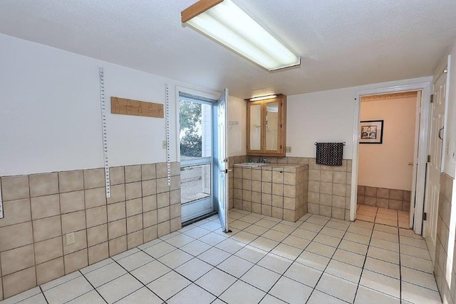 bathroom featuring tile patterned floors, a textured ceiling, and tile walls