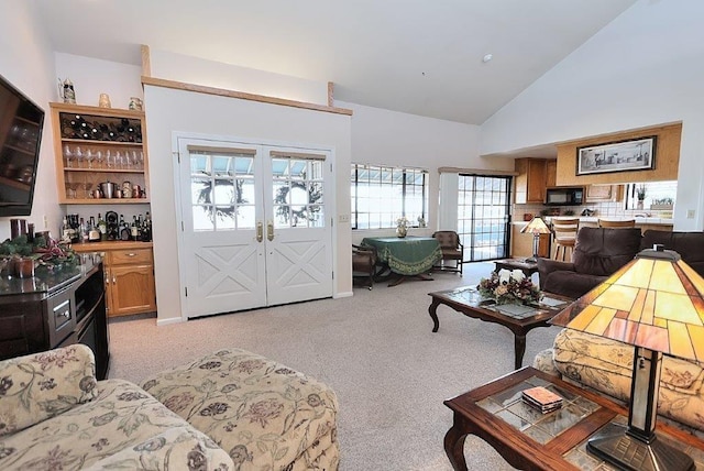 living room with light carpet, french doors, and high vaulted ceiling