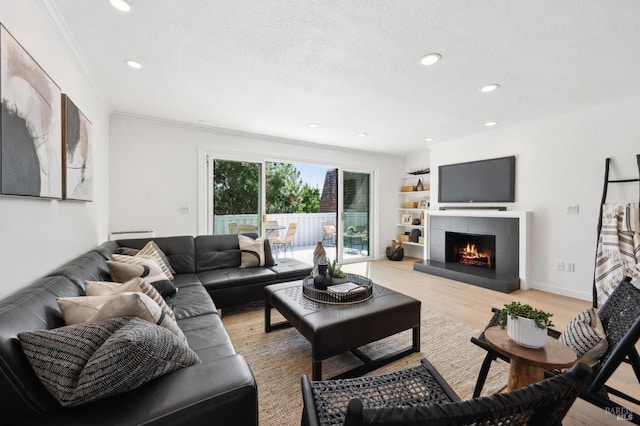 living room featuring recessed lighting, a textured ceiling, a fireplace, and light wood finished floors