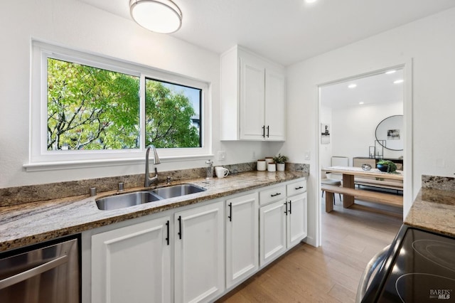 kitchen featuring stainless steel dishwasher, black range with electric cooktop, white cabinetry, and a sink