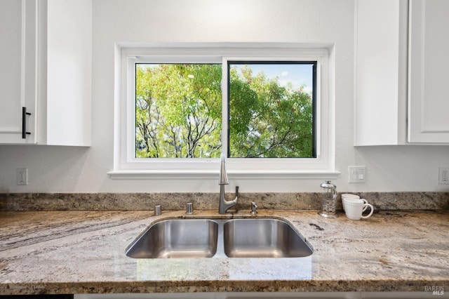 room details with light stone counters, white cabinets, and a sink