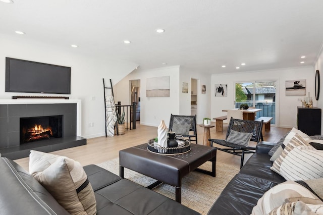 living area featuring recessed lighting, baseboards, crown molding, and light wood-style floors