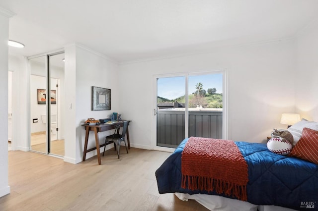 bedroom with access to exterior, light wood-style flooring, baseboards, and ornamental molding