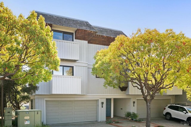 view of front of house with an attached garage, a shingled roof, and driveway