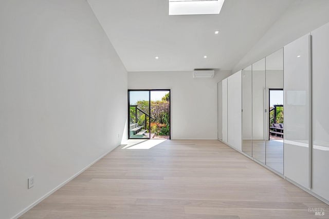 empty room featuring an AC wall unit, a skylight, and light wood finished floors