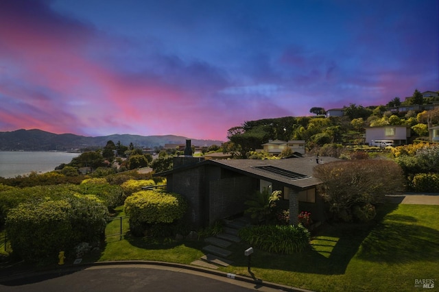 exterior space featuring fence, a lawn, and a water and mountain view